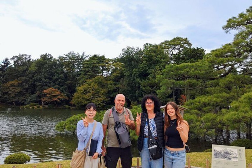 A group of people standing by a lake with trees in the background. 3