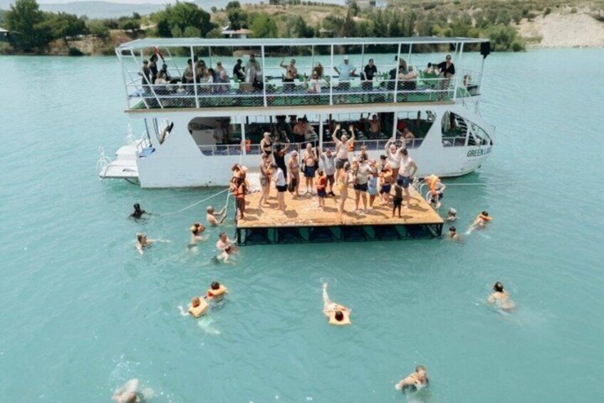 A boat with people swimming and standing on a platform in turquoise water. 1