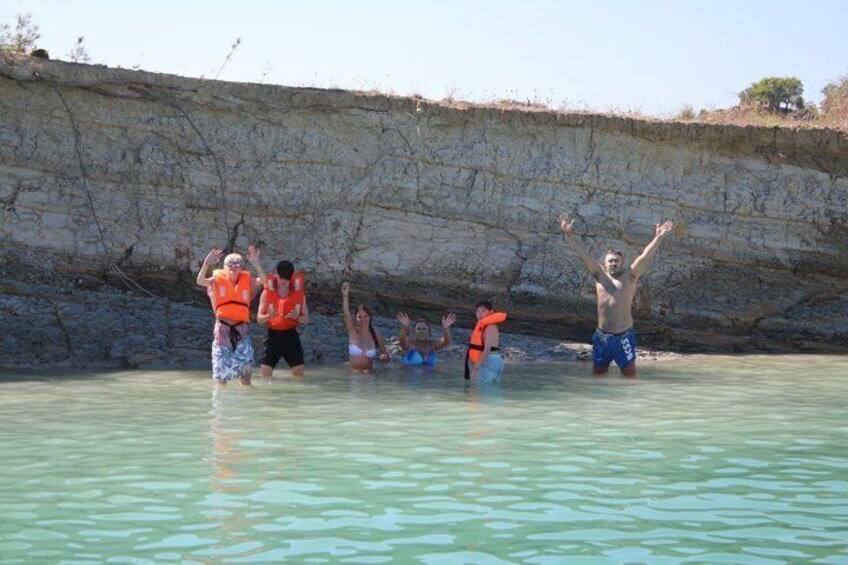 People in shallow water near a rocky cliff. 2