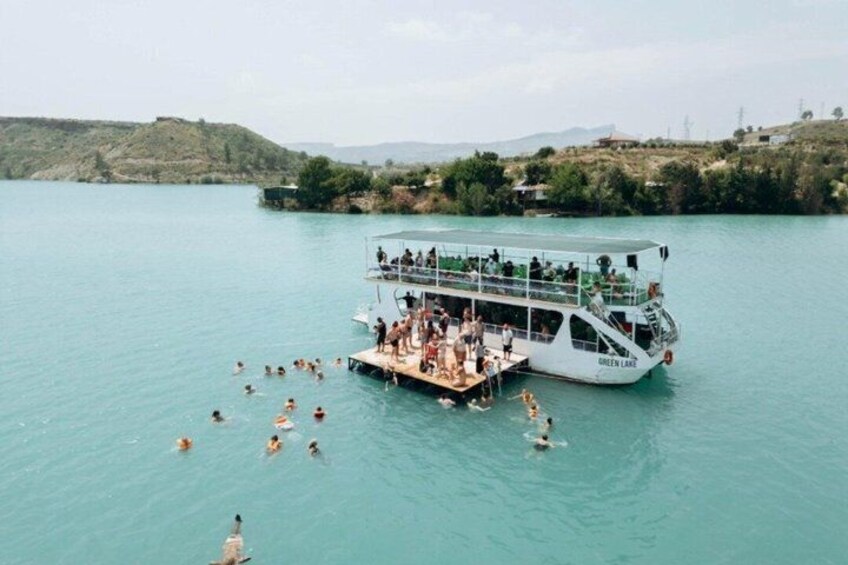 A boat named 'GREEN LANE' docked at a pier with people swimming in the water. 5