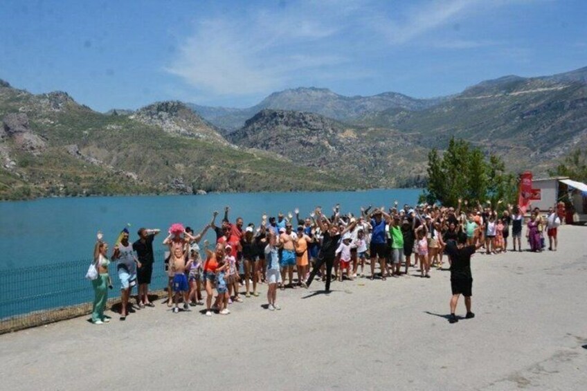 A group of people standing by a lake with mountains in the background. 4