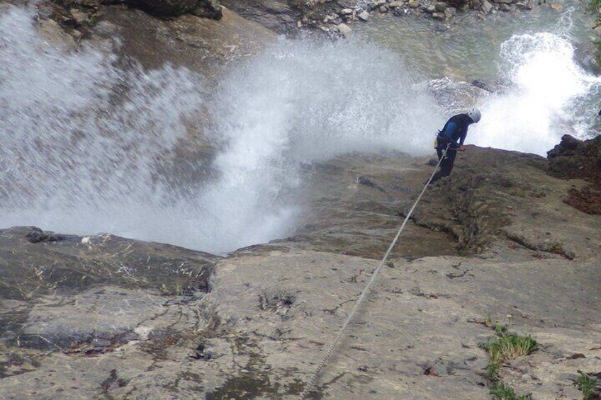 A person rappelling down a rocky cliff with a rope. 2