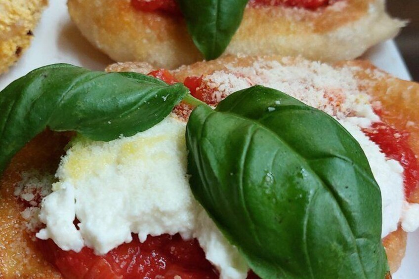 A close-up of a food item with a creamy topping, tomato sauce, and basil leaves. 4