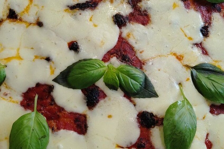 A close-up of a pizza with melted cheese and basil leaves. 1