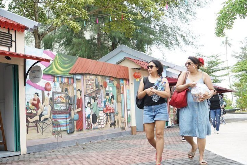A mural on a building, people walking on a sidewalk, and a street with trees. 2