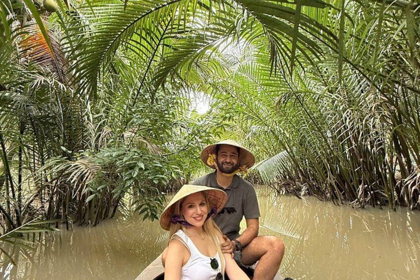 Two people in a boat surrounded by dense palm trees and water. 4