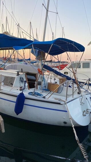 A sailboat docked at a marina with multiple boats and masts visible in the background. 2