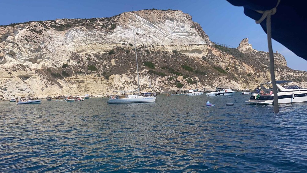 A coastal area with boats on the water and a rocky cliff in the background. 4
