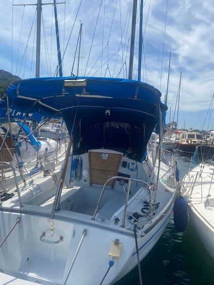 A sailboat docked at a marina with other boats, a blue canopy, and a clear sky. 3