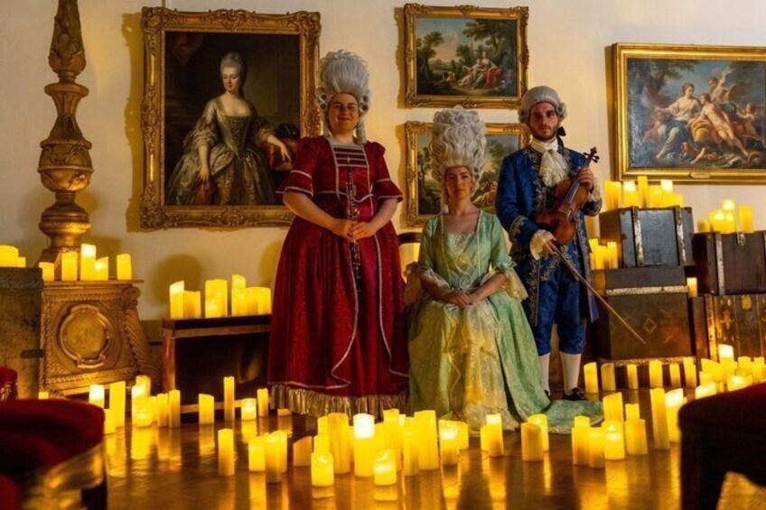 A room with historical paintings, a candle-lit table, and figures dressed in period costumes. 1