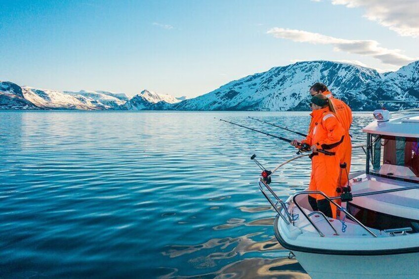A person fishing on a boat with snow-capped mountains in the background. 1