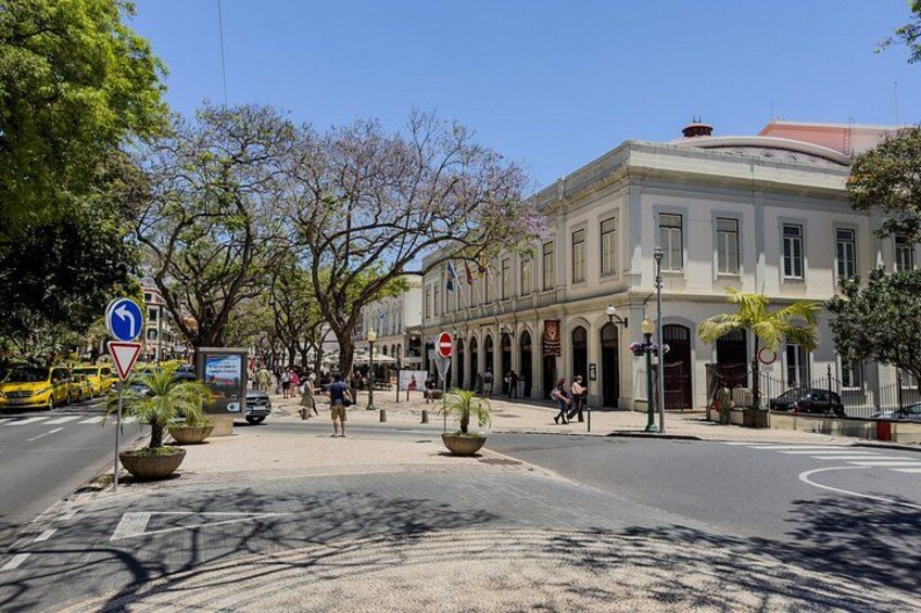 A street with a roundabout, buildings, and pedestrians. 4