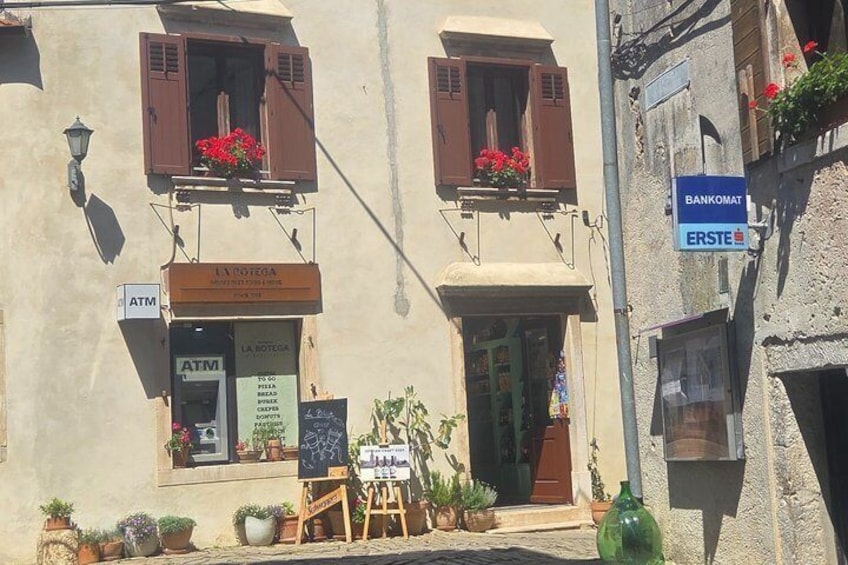 A building with an ATM, a sign for 'LA NOTEGA,' and a 'BANKOMAT ERSTE' sign. 3