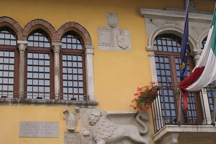 A yellow building with arched windows, a lion sculpture, and a plaque. 5