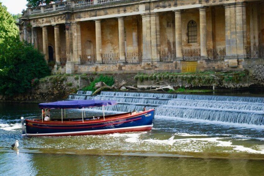 A boat with a blue canopy on a river, a waterfall, and a classical building with columns. 3