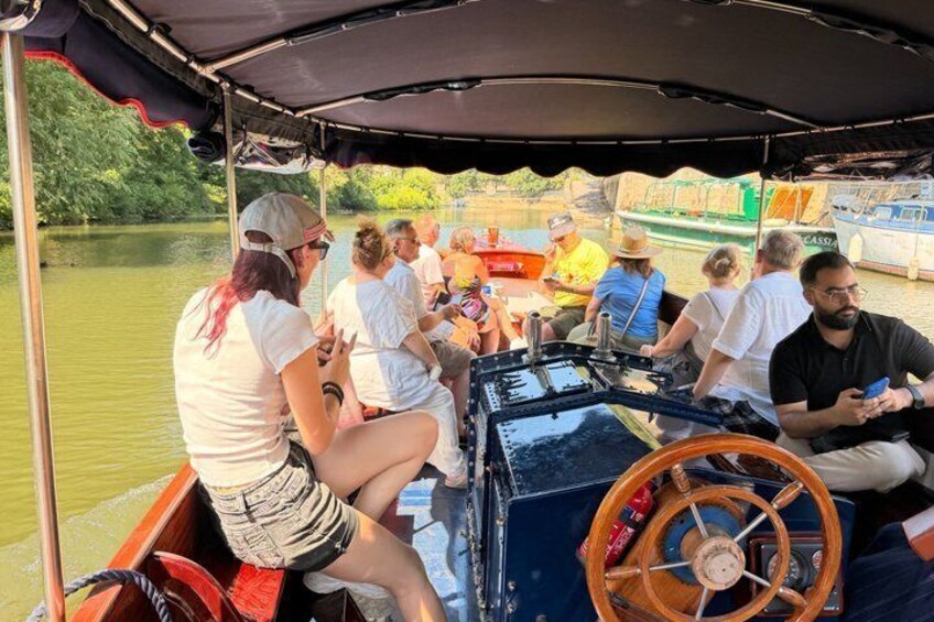 A group of people on a boat with a steering wheel and a canopy overhead. 4