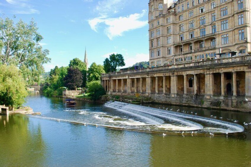 A river with a water mill, a bridge, and a historic building with columns. 2