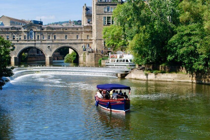 A river with a boat, a bridge, and a building in the background. 1