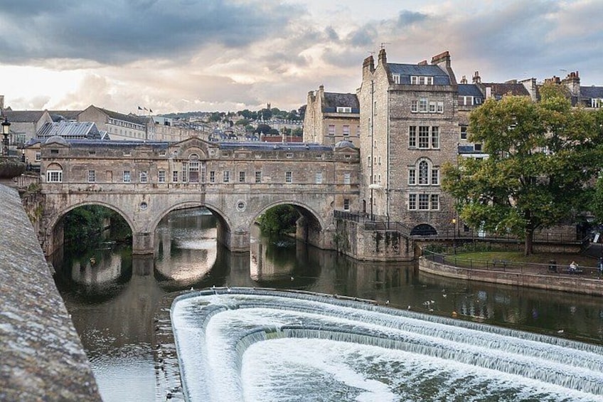 A stone bridge over a river with a castle in the background. 2