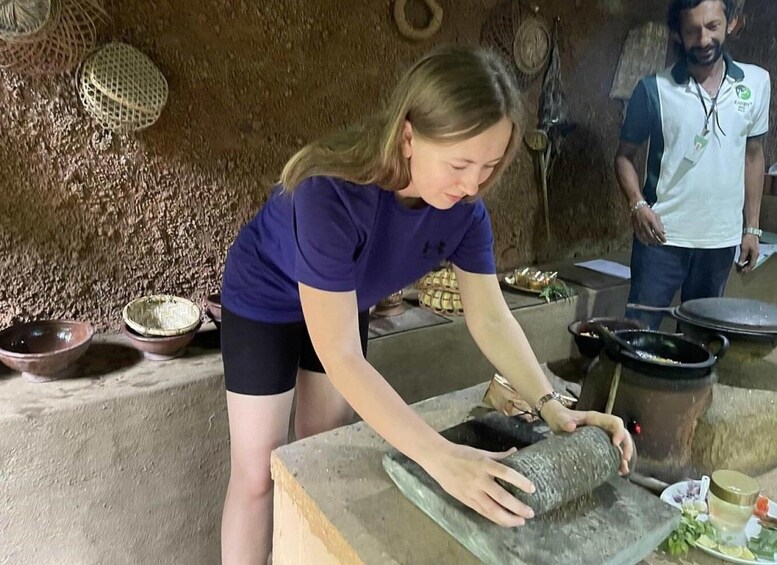A person using a mortar and pestle, with bowls and a large pot in the background. 3