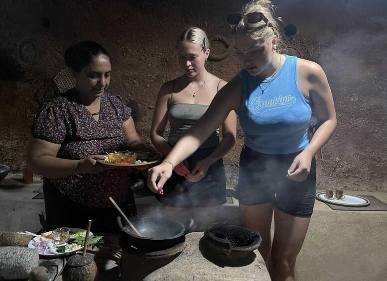 Three people cooking outdoors with a pot on a stove and a plate of food. 5