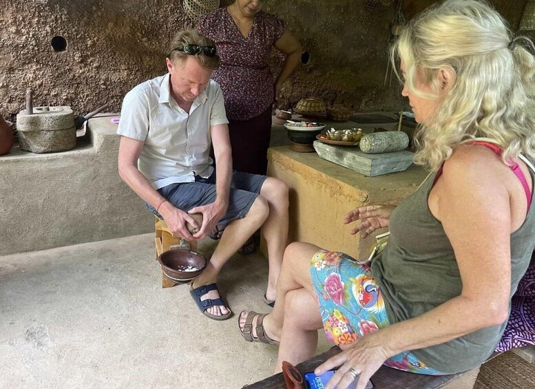 A man sitting on a stool, peeling a potato. 4