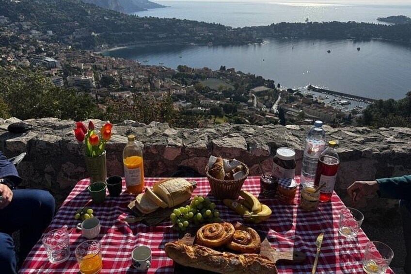 A picnic table with food and drinks overlooking a coastal landscape. 1