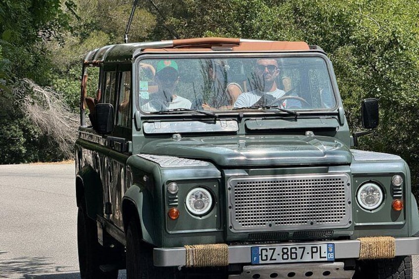 A green off-road vehicle with passengers, license plate GZ-867-PL, driving on a road with trees in the background. 5