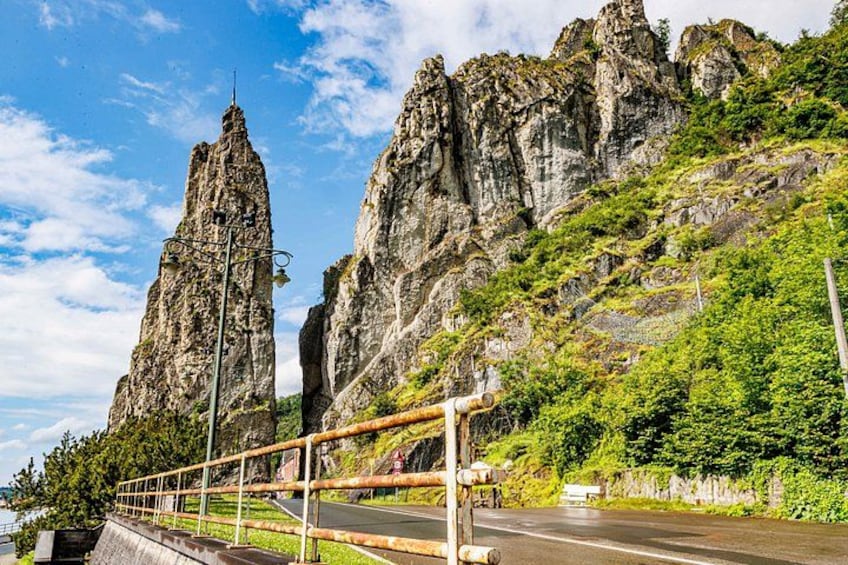A bridge with a guardrail, a road, and rocky cliffs. 5
