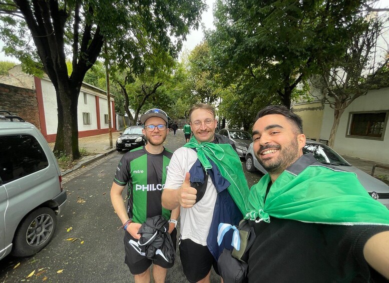 Three people taking a selfie on a street with parked cars and trees. 2