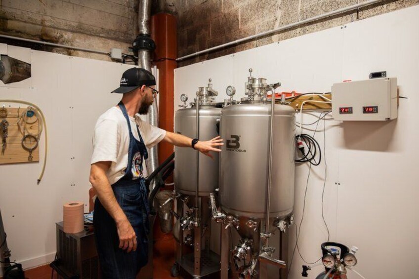 A person operating a large industrial machine with two tanks, surrounded by pipes and gauges. 4