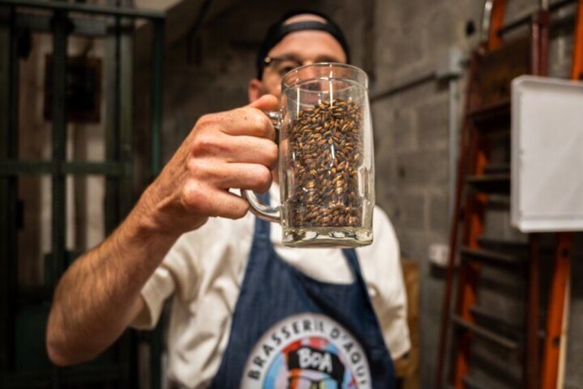A person holding a glass mug filled with coffee beans. 1