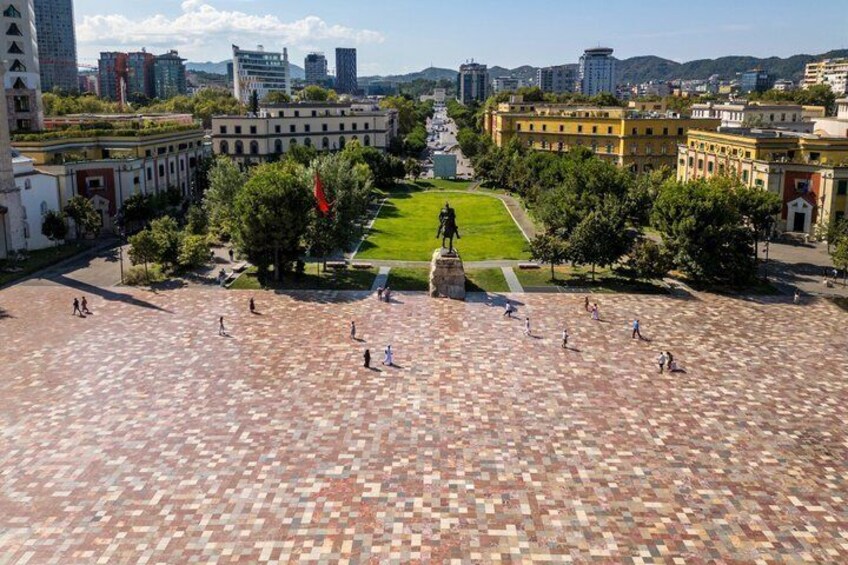 A plaza with a central statue, surrounded by buildings and trees. 3