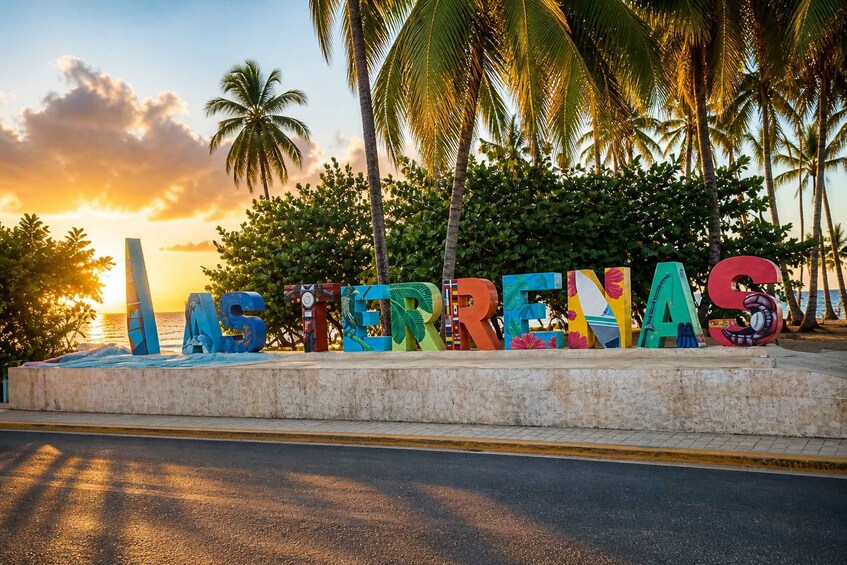A beachside sign with colorful letters spelling 'ASTERIAS' against a sunset backdrop. 1