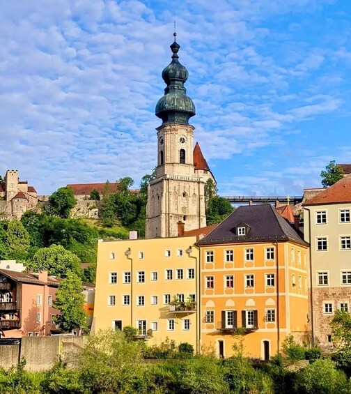 A historic tower with a clock, surrounded by colorful buildings and lush greenery. 2