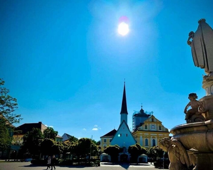 A church with a tall spire, a statue on a fountain, and a clear blue sky. 4
