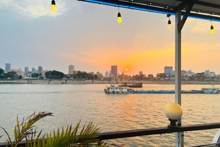 A sunset over a river with boats, city skyline, and a bridge. 5