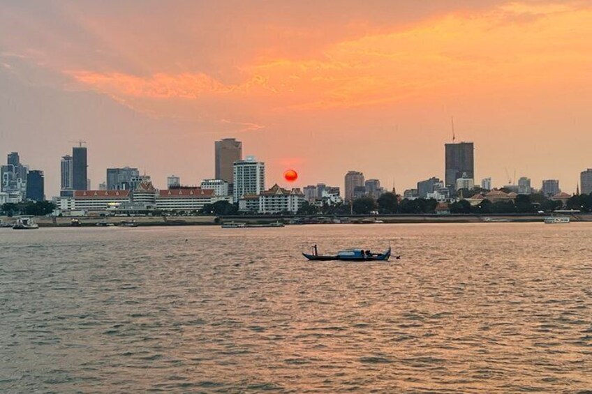 A sunset over a city skyline with buildings and a boat on the water. 3