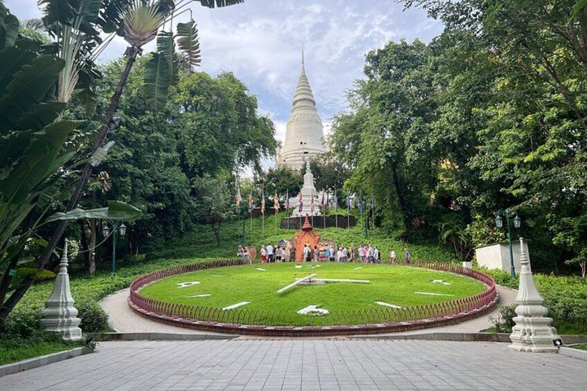 A white stupa surrounded by a circular garden with a paved walkway. 2