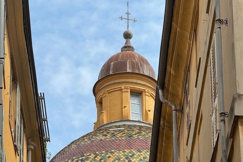 A domed building with a colorful mosaic roof and a cross on top. 1