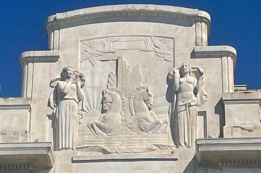 A stone monument with relief sculptures of a woman and a horse, and another woman standing beside it. 3