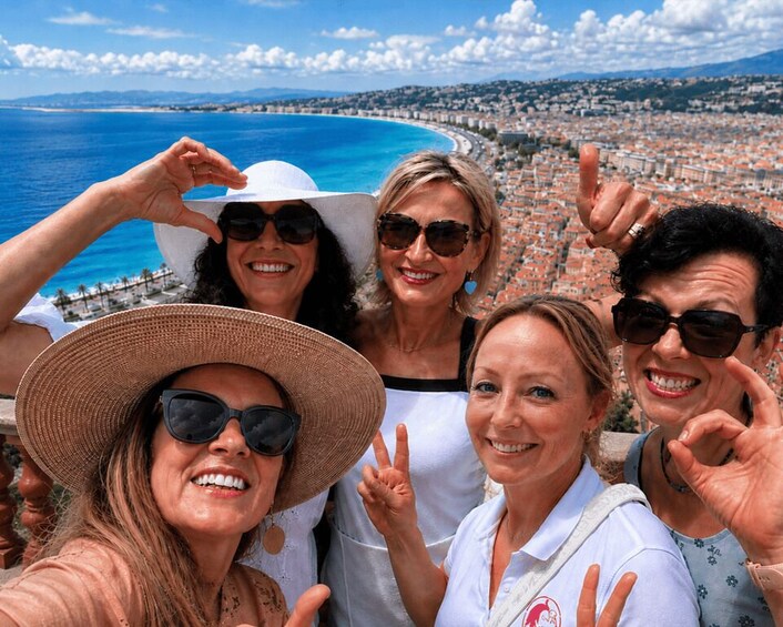 A group of people taking a selfie with a coastal cityscape and ocean in the background. 1