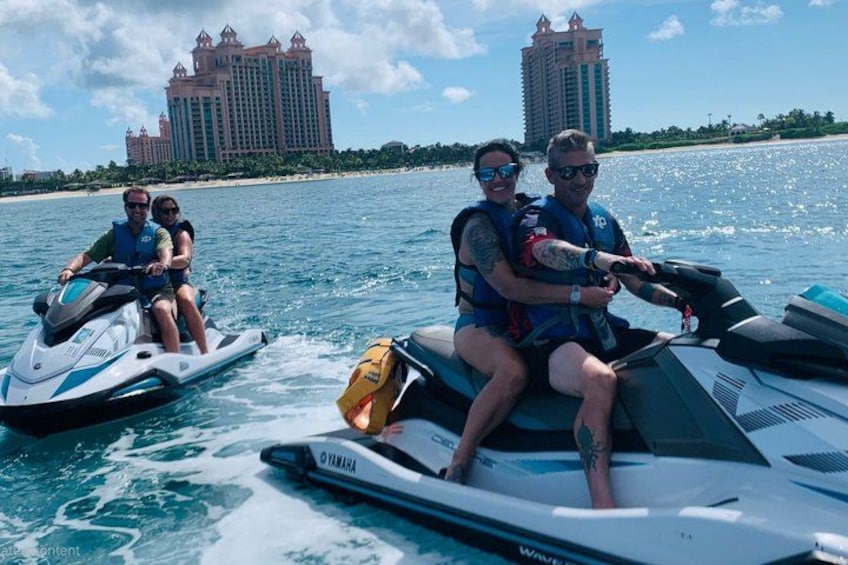 Two people on jet skis with a large building in the background. 3
