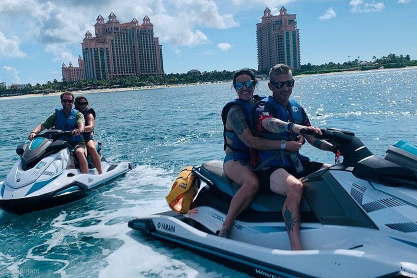 Three people on jet skis on a body of water with a large resort building in the background. 3
