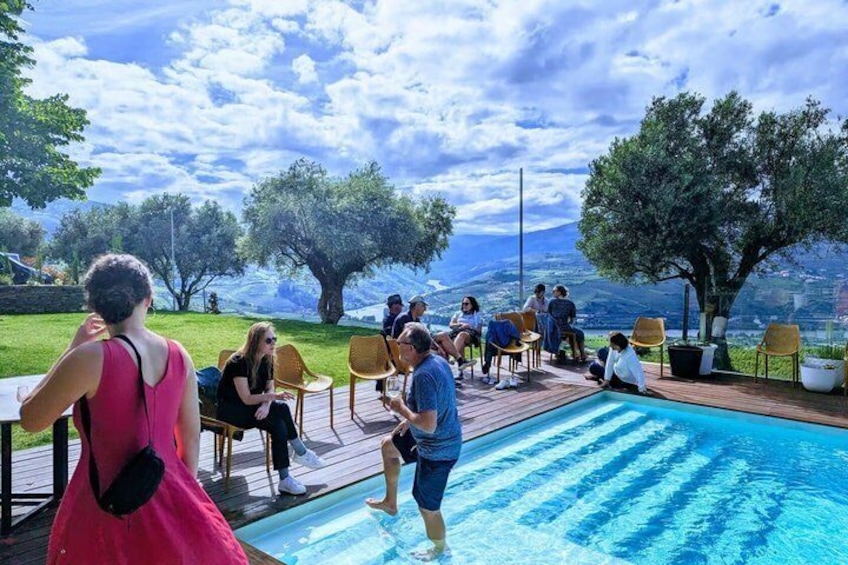 A group of people around a pool with a scenic view of trees and a distant landscape. 1