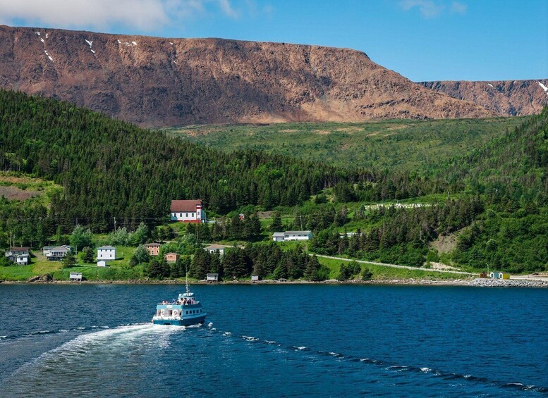 A boat on a calm lake with a mountainous backdrop and a small settlement. 1