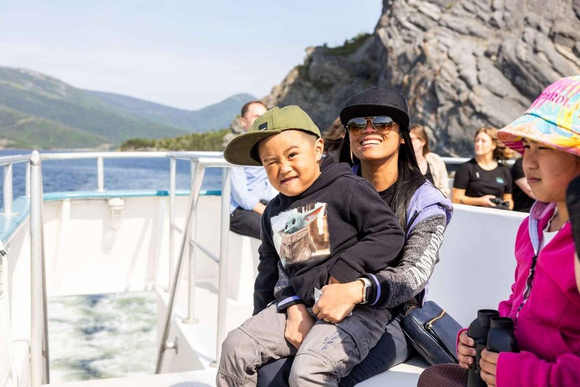 People on a boat with a rocky coastline and mountains in the background. 2