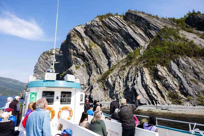 A boat with passengers observing a rocky cliff. 3
