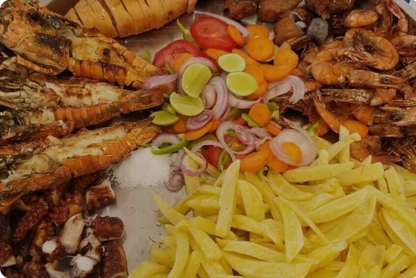 A variety of seafood including lobster, shrimp, and fish, along with sliced vegetables like tomatoes, onions, and carrots. 4