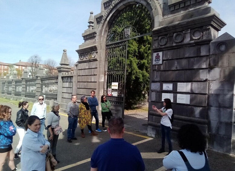 A group of people standing in front of a large, ornate gate with inscriptions and plaques. 1